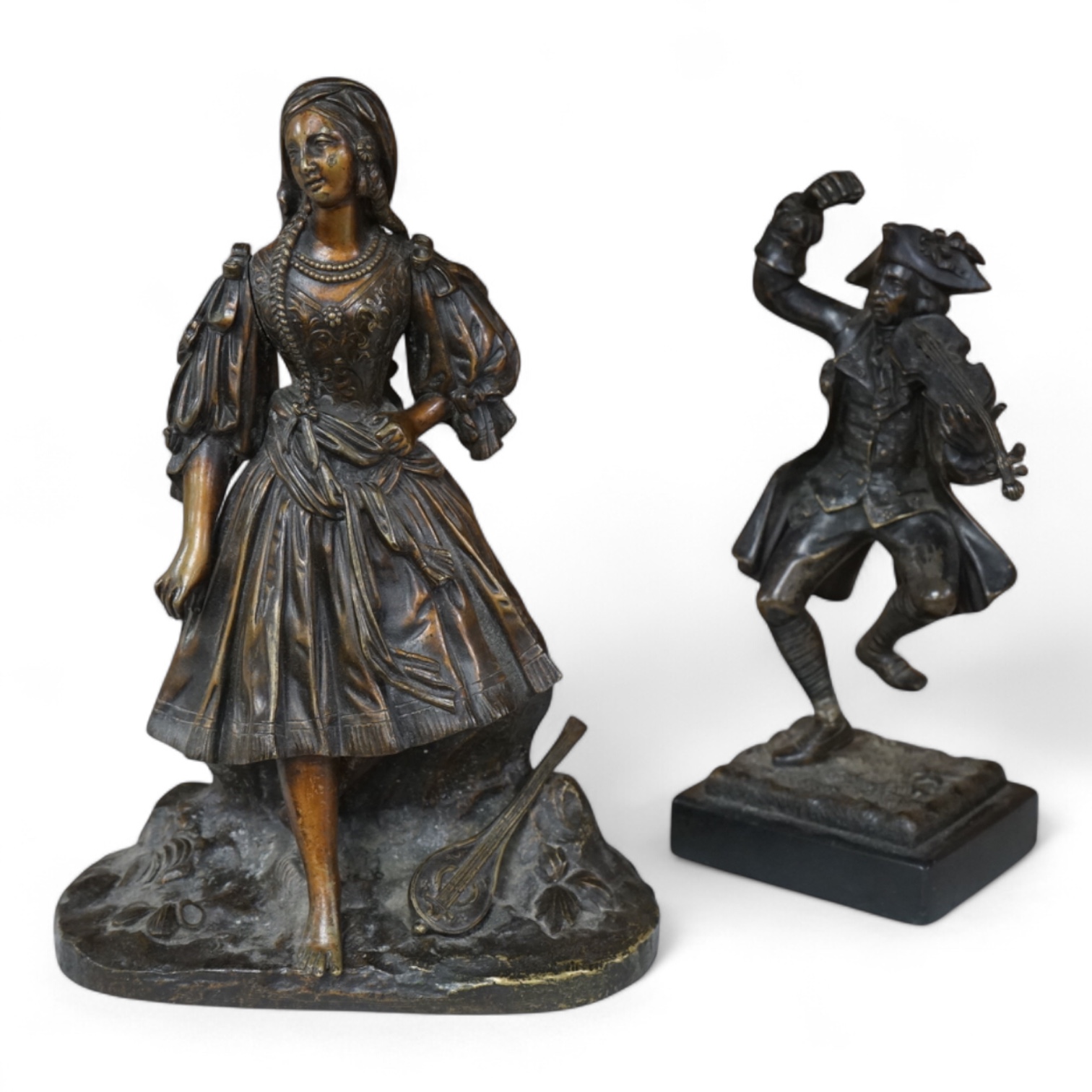 A small bronze figure of a male violinist and another bronze female figure with a lute against a rock, tallest 23cm high